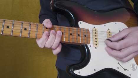 musician playing an electric guitar, focusing on hand movements and fretboard technique as he picks each string