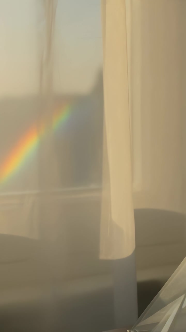 Vertical video: Appearing rainbow patch moving on sheer drape, sun through window bending via prism
