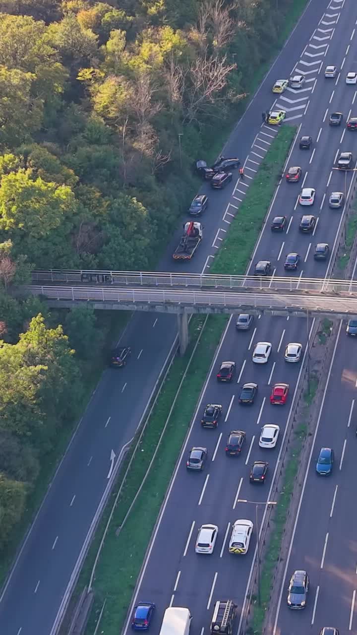 Vertical aerial drone over the Waterworks Roundabout, A406 London. A police car blocks an exit, while slip road accident involving four cars causes congestion, delays, and rubbernecking traffic