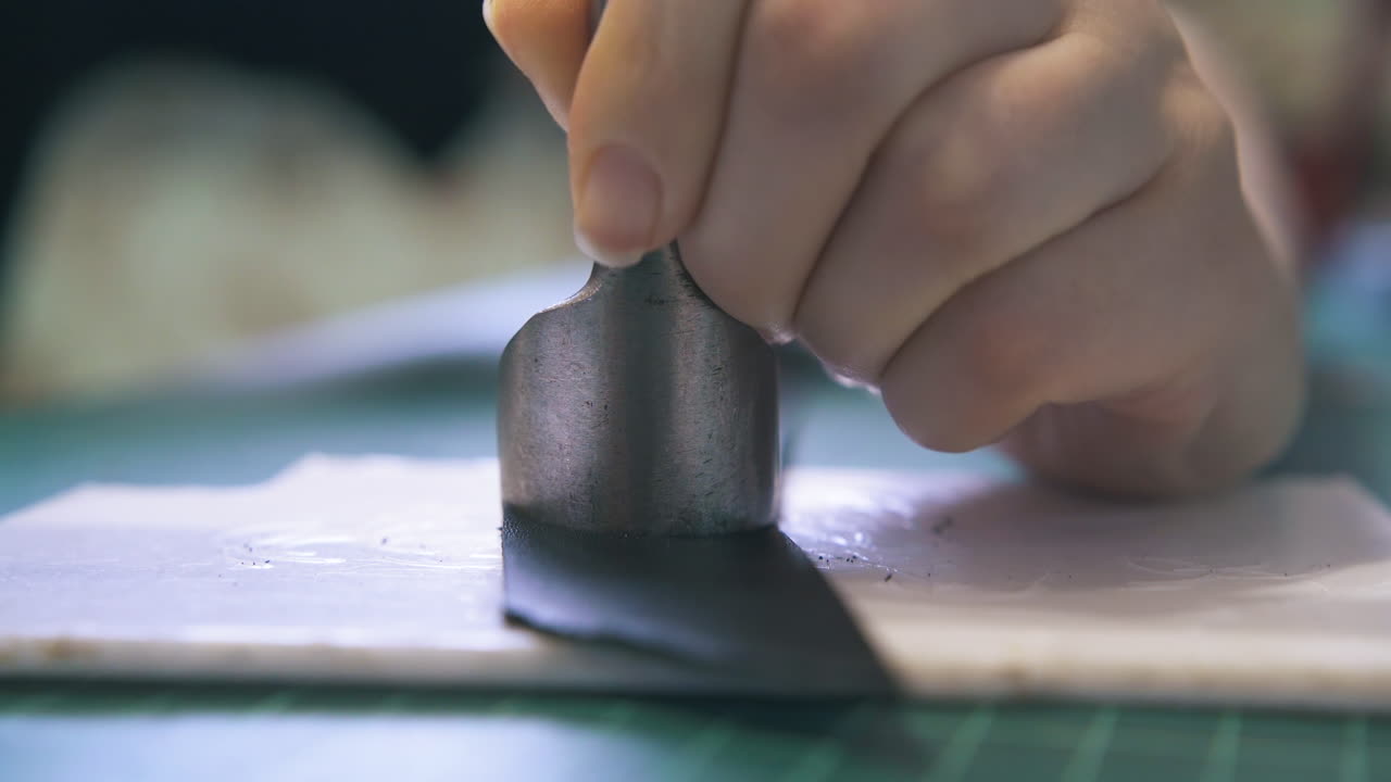 세일러는 모 ⁇ 이 절단기로 검은 가죽 벨트 가장자리를 잘라줍니다.