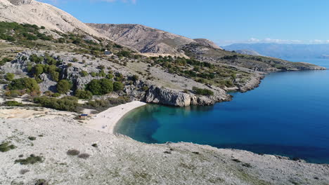 luftaufnahme, die einen kleinen strand enthüllt, der zwischen bergen in der nähe des dorfes baska versteckt ist