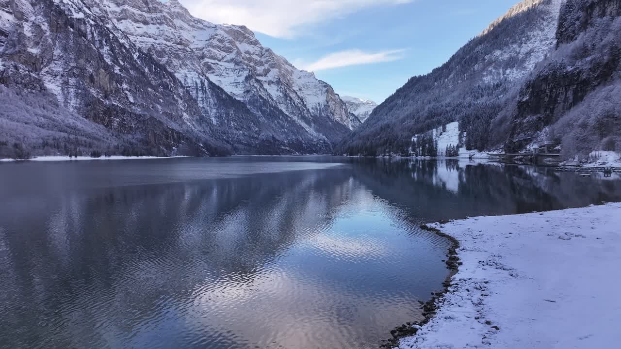 Klöntalersee Glarusissa, Sveitsissä, lumisten vuorten ja kirkkaiden heijastusten ympäröimänä.