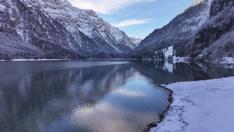 klöntalersee in glarus, switzerland, surrounded by snowy mountains and clear reflections