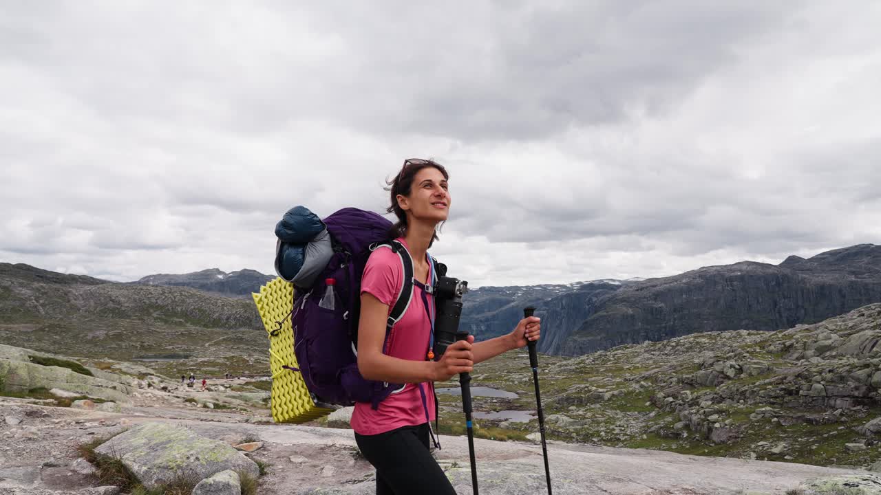 Woman hiking in Norway with a backpack, looking up in awe at the mountain view