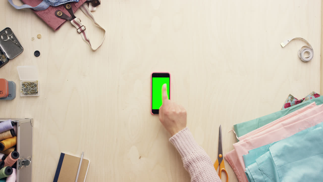 vista superior de las manos del diseñador de moda usando una aplicación de diseño de teléfono móvil trabajando en el escritorio desde arriba - dragón épico rojo