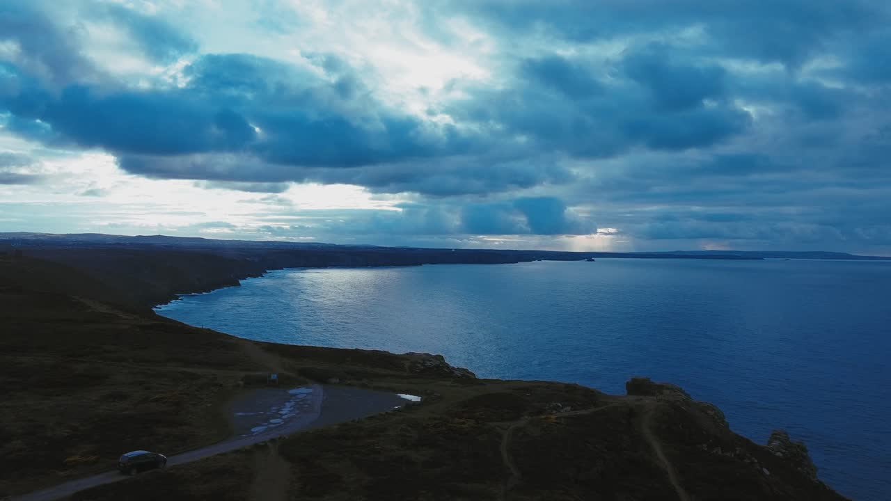 Aerial shot of some Cornish cliffs with a car driving along in shot