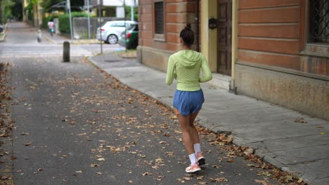mujer corriendo por la calle de la ciudad en otoño