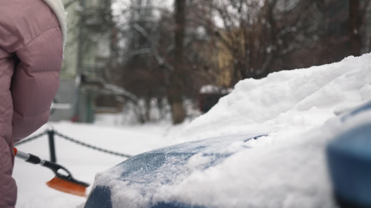 여자 가 차 에서 눈 을 제거 하고 있다