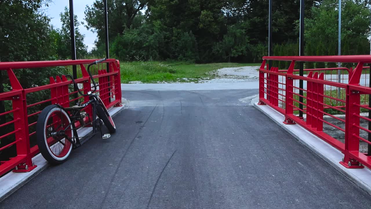 на кадре изображен велосипед в стиле вертолета или велосипед с белыми колесами на невесте с красными перилами, окруженный природой в разрешении 4k