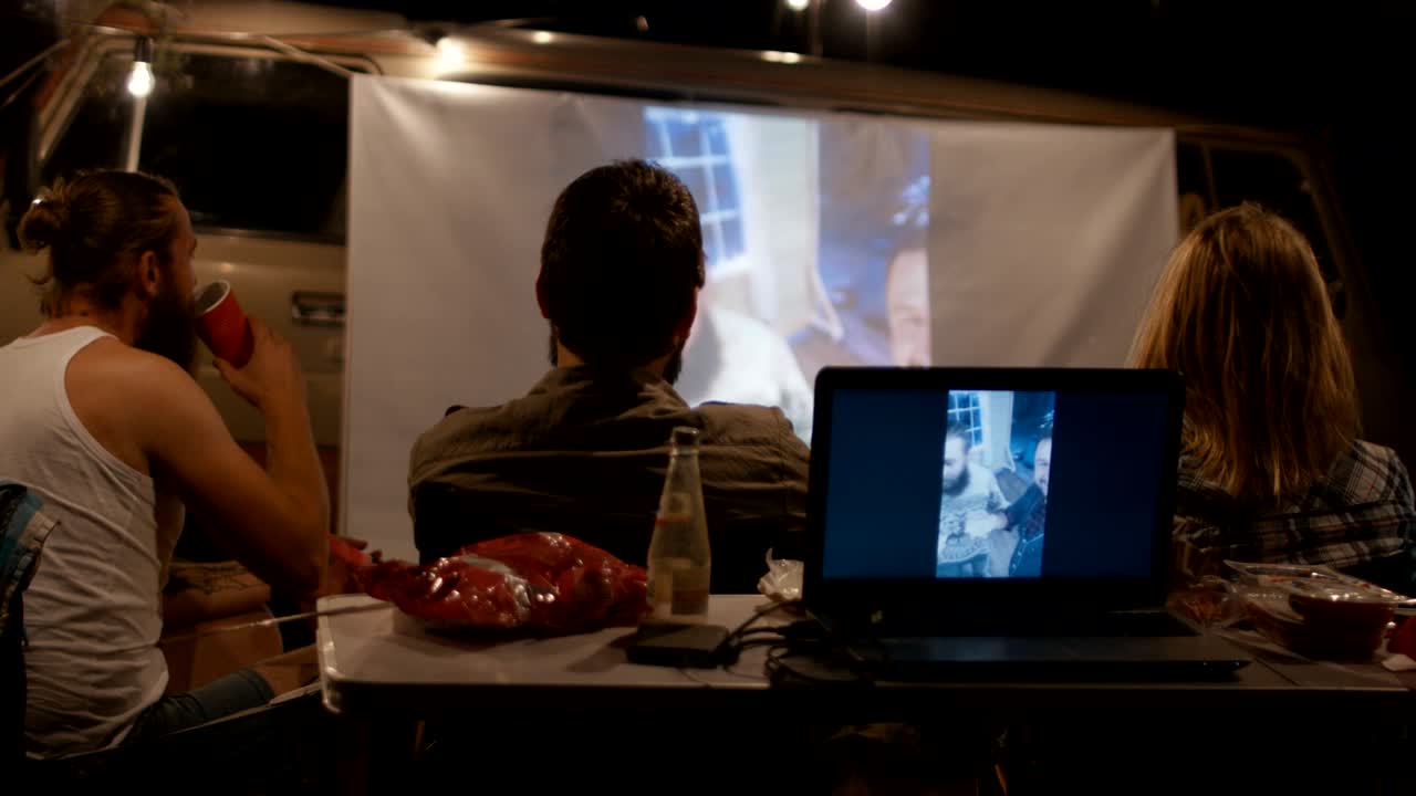 amigos viendo una película en la pantalla en el campamento
