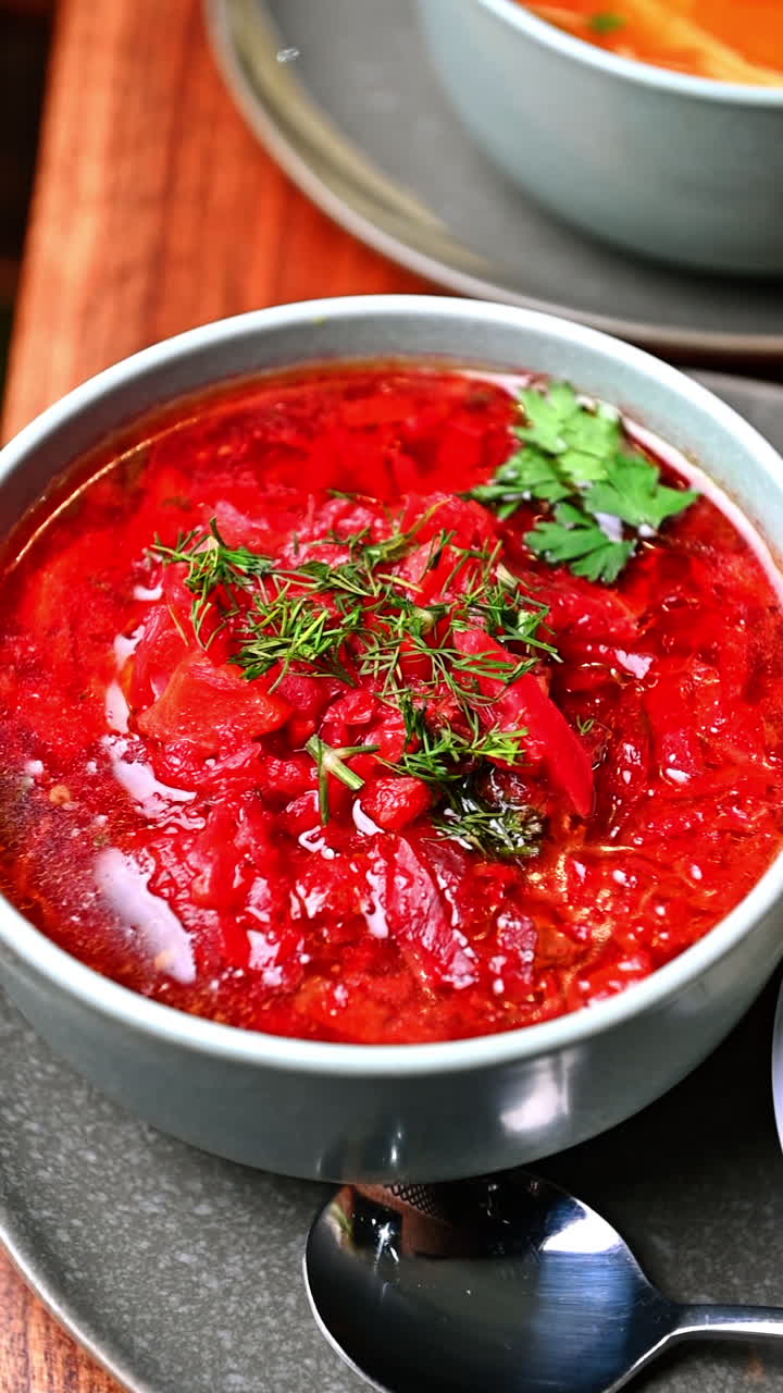 Close-up of traditional borscht soup with beetroot and herbs. Red Ukrainian borscht with beetroot, cabbage, and herbs served in ceramic bowl with sour cream on side