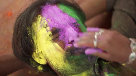 indian man close-up of face smeared with bright holi colors