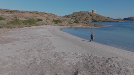 Langhaarige-Frau-Starrt-Auf-Das-Blaue-Meer,-Luftdrohne-Fliegt-über-Den-Weißen-Sandstrandklippen-Von-Cala-Sa-Torreta,-Menorca,-Spanien