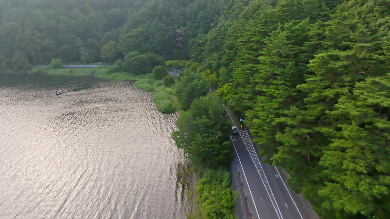 Drone following a car driving on a coastal road at lake Kawaguchi, summer in Japan