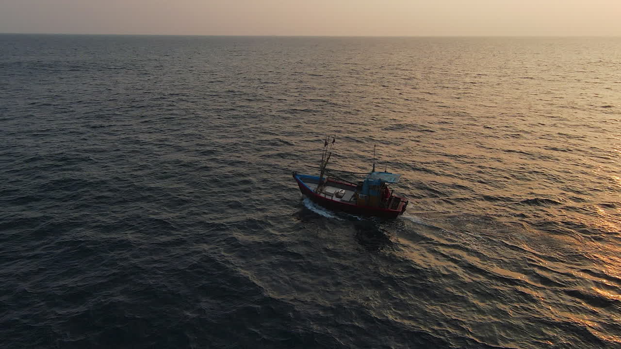 Ripresa orbitale FPV di una piccola barca che naviga nell'oceano blu con uno splendido riflesso del sole, Sri Lanka