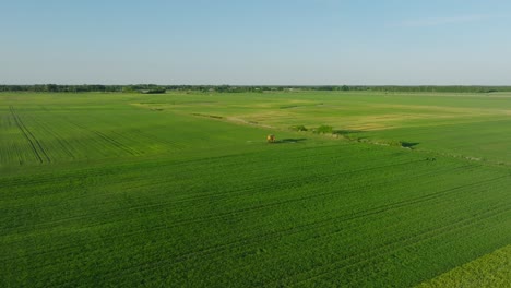 Vista-Aérea-De-Un-Agricultor-Rociando-Campos-De-Cultivo-Con-Tractores,-Pesticidas-Y-Fertilizantes,-Tarde-Soleada-De-Verano,-Luz-De-Hora-Dorada,-Amplio-Tiro-De-Drones-Avanzando