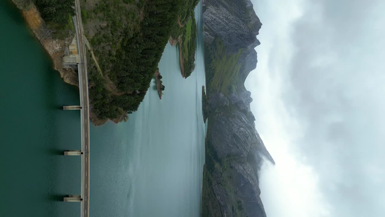 fotografía aérea del lago riaño en picos de europa, españa, con cielos nublados, aguas azules tranquilas, acantilados de montaña y árboles verdes exuberantes