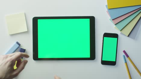 el diseñador está usando tableta y teléfono móvil con pantalla verde. genial para el uso de maquetas.