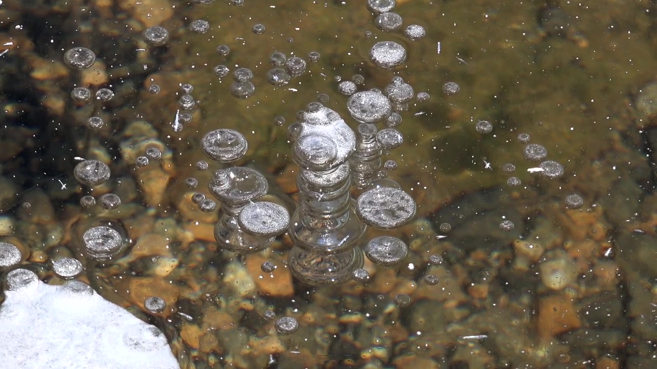 Bolhas de Ar Presas Sob Fina Camada de Gelo em Leito de Rio Raso