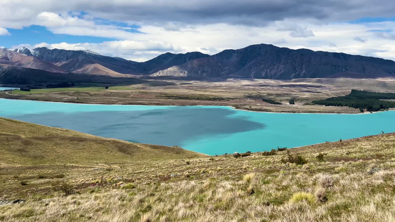 Turquoise lake under cloudy sky in New Zealand's scenic landscape