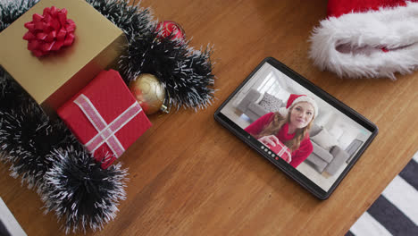 Lächelnde-Kaukasische-Frau-Mit-Weihnachtsmütze-Bei-Weihnachtsvideoanruf-Auf-Dem-Tablet