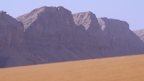 fossil rock - iconic rock formation in arid desert sand dunes in sharjah, united arab emirates - wide shot