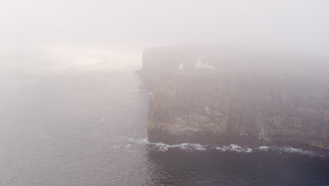 Aerial-wide-shot-of-a-clifftop-Lighthouse-on-a-misty-morning-on-the-north-coast-of-Scotland