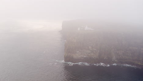 Toma-Aérea-Amplia-De-Un-Faro-En-Lo-Alto-De-Un-Acantilado-En-Una-Mañana-Brumosa-En-La-Costa-Norte-De-Escocia