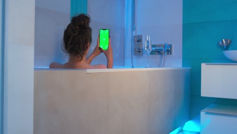 green screen, chromakey of phone. greenscreen of chromakey mockup. female shopping online or chatting lying in bathtub