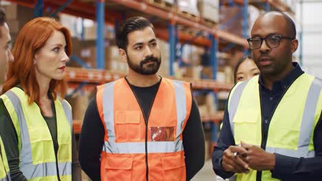 team meeting in a warehouse: employees engage in a discussion while reviewing safety protocols and operations within a busy storage facility
