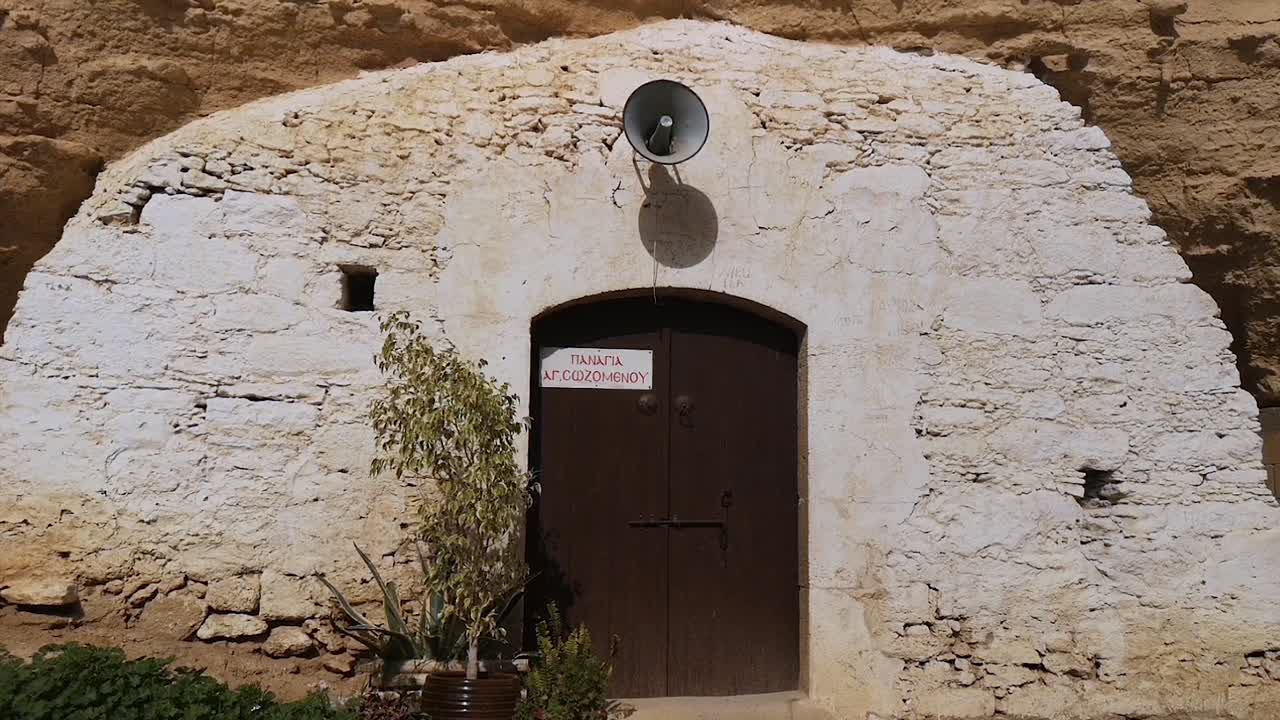 Una giovane ragazza si avvicina alla porta della chiesa rupestre di Agois Sozomenos a Cipro, Europa