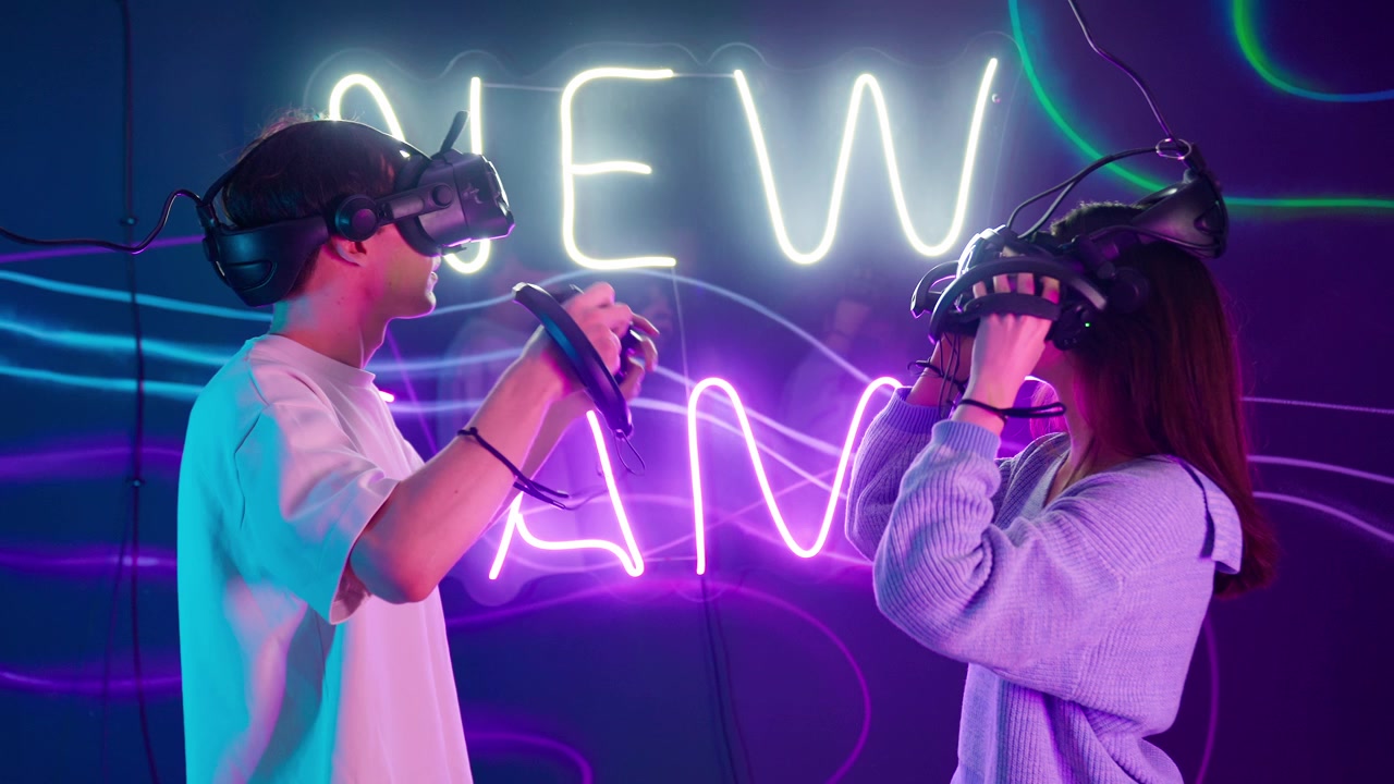 Nuori pariskunta pukee VR-lasit päähänsä neonvaloin valaistussa huoneessa