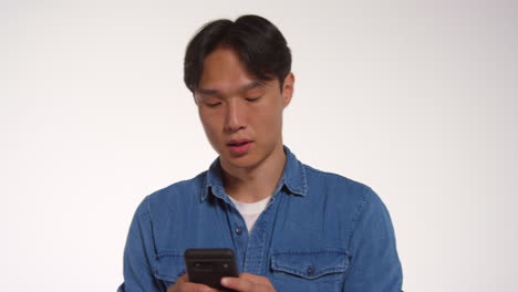 man with mobile phone in front of white studio background posing for photo booth style portraits