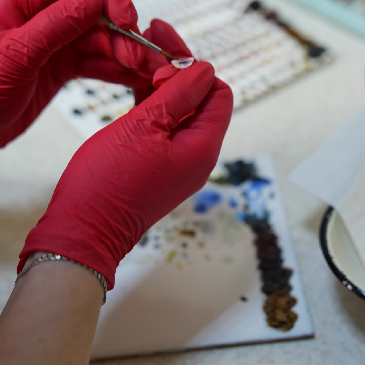 Master is painting artificial eye. Medical technician uses colors and special brush for making eye prosthesis