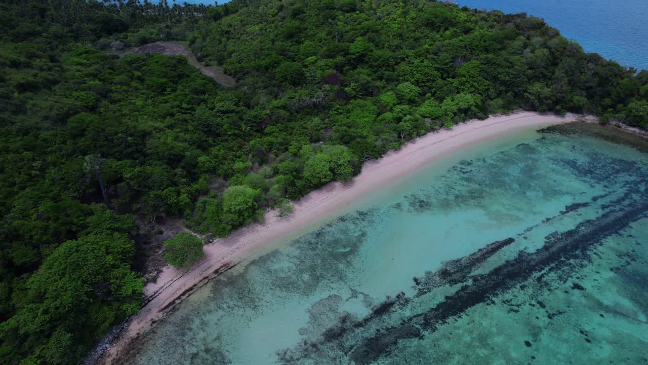 Aerial View showcasing a tropical beach with clear turquoise waters, lush green coastline, and a serene bay in the Philippines. Orbit Motion