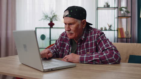 Stressed-upset-senior-grandfather-man-working-on-laptop-computer,-received-bad,-loss-news-at-home