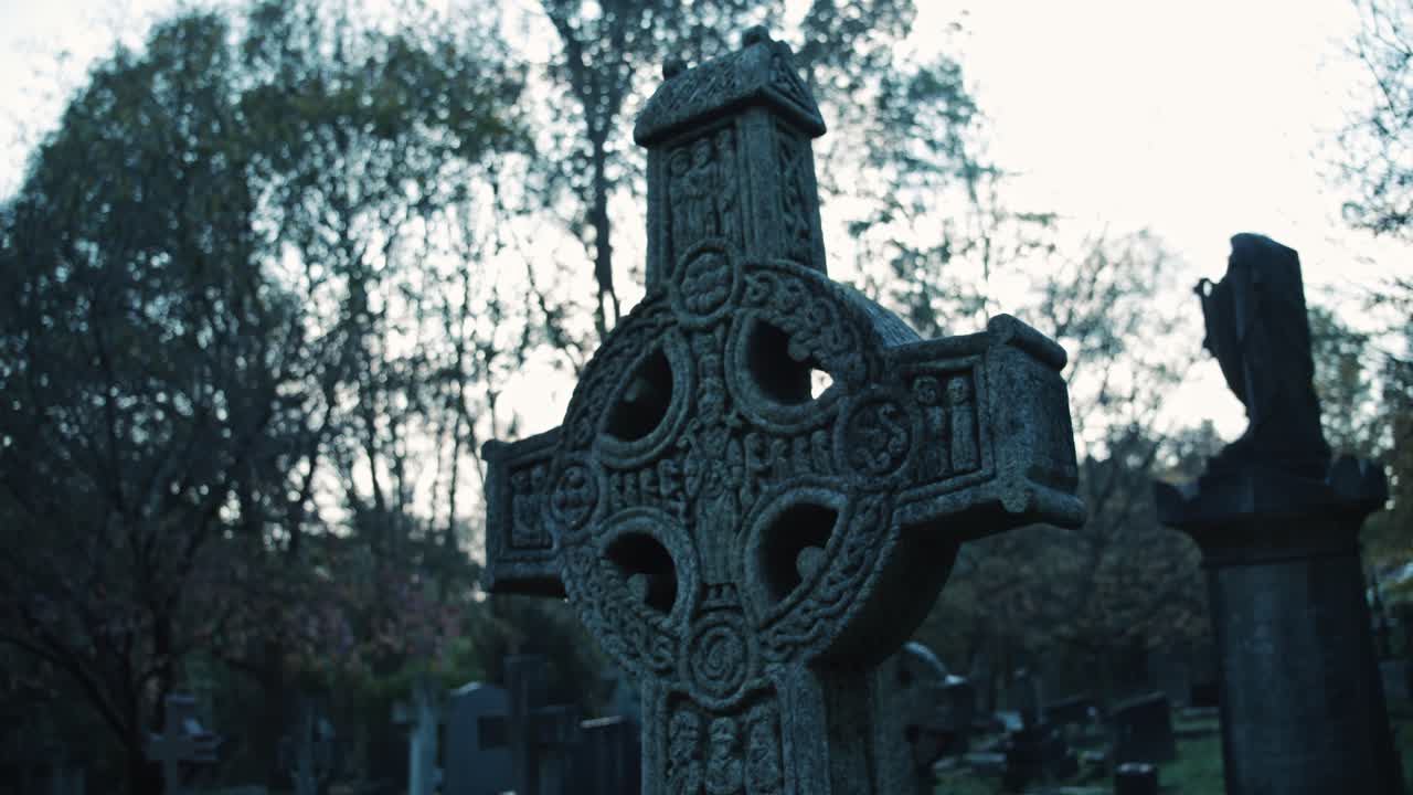 una cruz gótica decorada de una tumba en un cementerio inglés