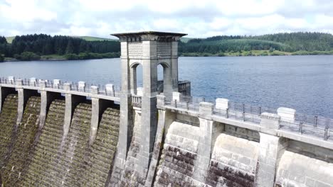 Alwen-reservoir-Welsh-woodland-lake-water-supply-aerial-view-concrete-dam-countryside-park-slow-pull-back-reveal