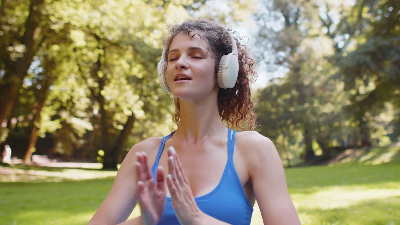 mujer sentada en una alfombra en posición de loto relajándose practicando meditación de yoga en el parque en un día de verano