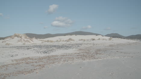 beach with mountains in the background, few clouds in the sky