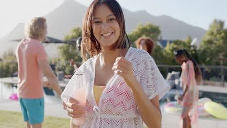 portrait of happy biracial woman dancing in the sun at pool party with diverse friends, slow motion