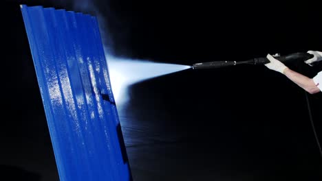 cleaning a blue metal sheet with a pressure washer