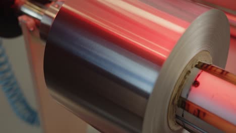 a big roll of aluminum foil on a feeder of the cutting machine - boom down close up shot