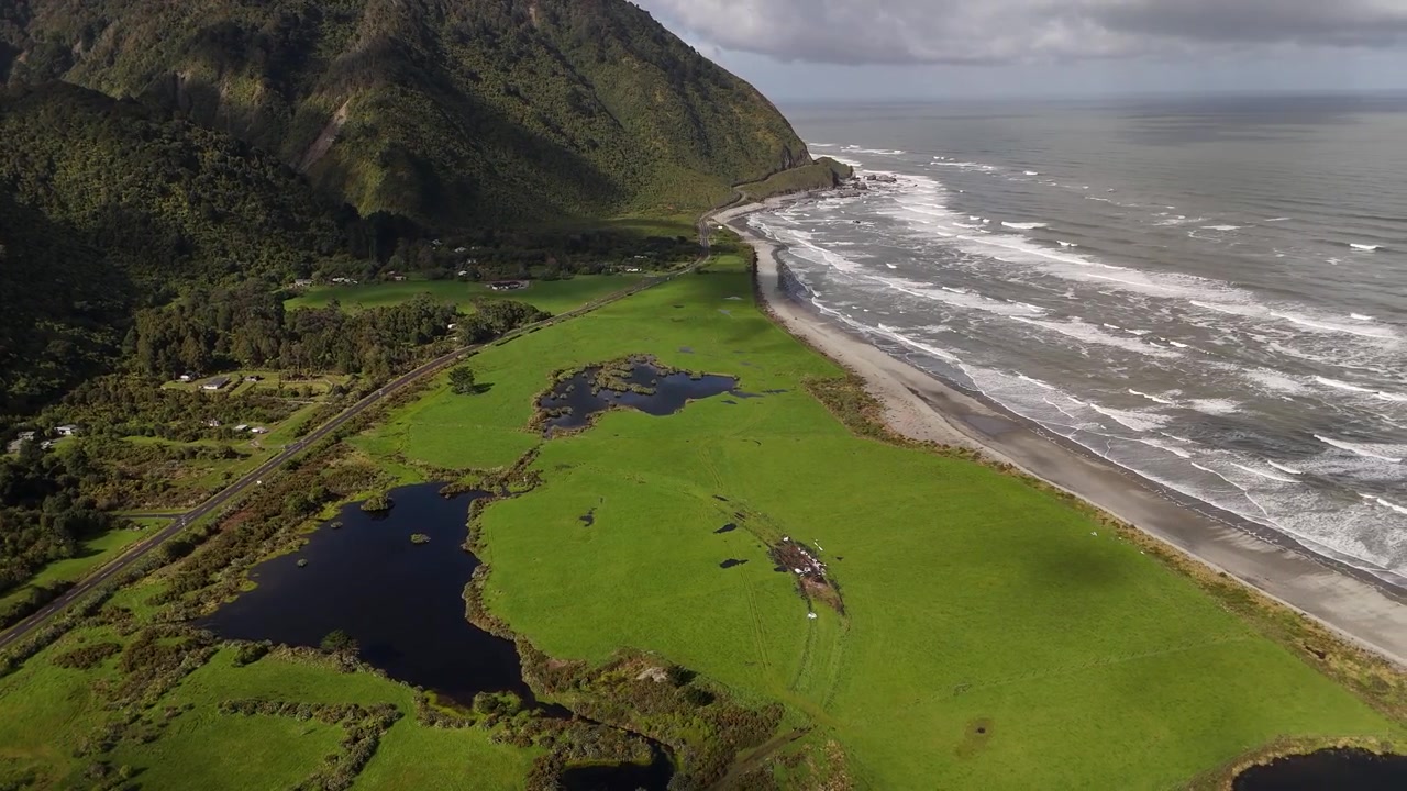 Ripresa aerea con drone di una zona umida costiera accanto alla spiaggia oceanica, con panoramica a destra