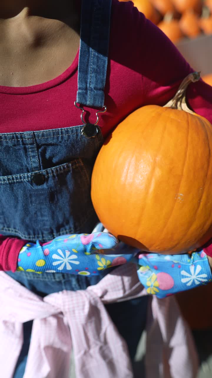 niño sosteniendo una calabaza en un parche de calabaza