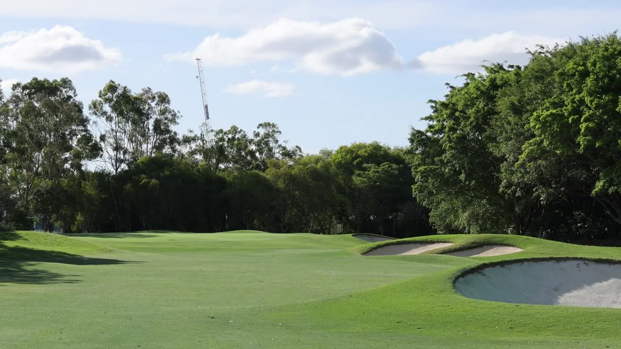 Ampia vista panoramica di un fairway ben curato di un campo da golf con trappole di sabbia bianca e alberi