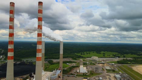 Flying-past-an-active-smokestack,-with-a-beautiful-Tennessee-country-landscape-in-the-background