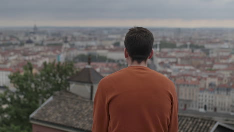 a young man sitting in front of a beautiful view of the city of lyon in france