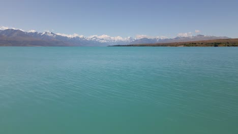 soaring low over the tranquil lake pukaki in new zealand, towards mt cook and the southern alps