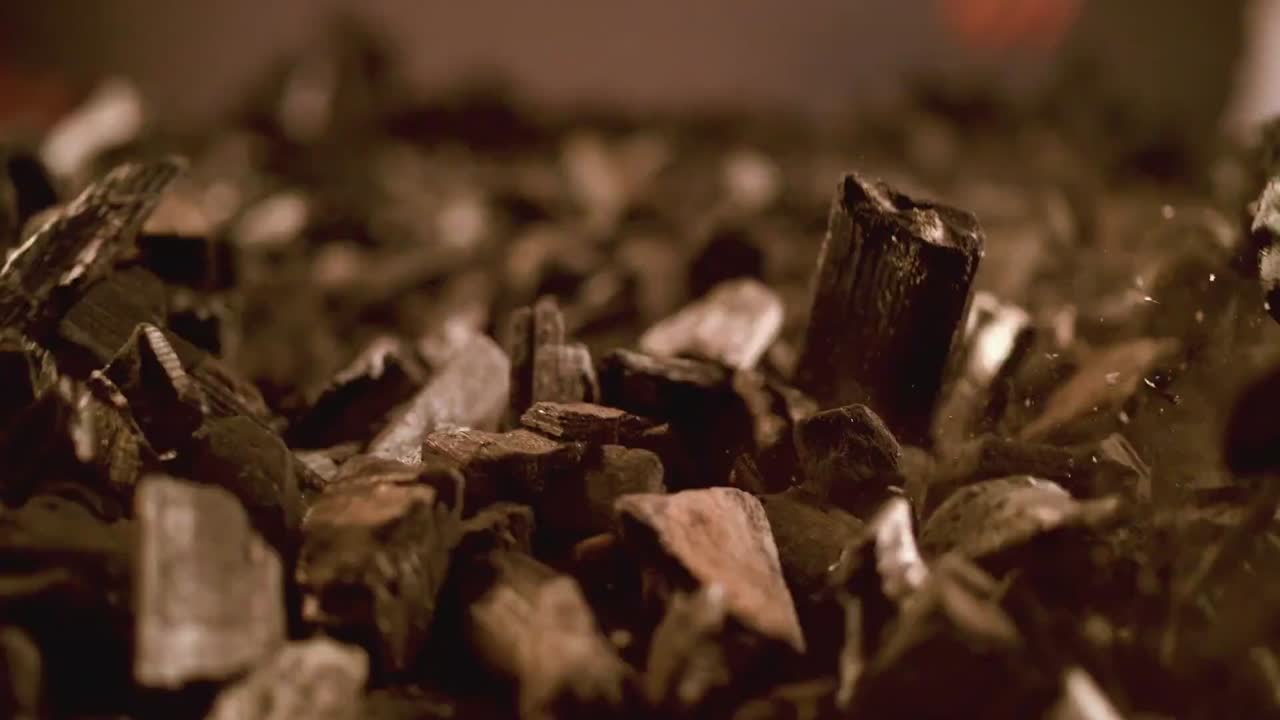 el carbón, una roca sedimentaria combustible, que estalla desde la superficie del suelo, emite polvo, simbolizando el concepto de extracción de energía e impacto ambiental